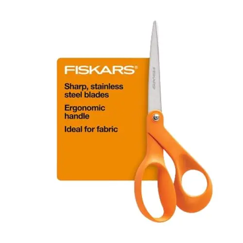 Classic Fiskars orange-handled scissors cutting fabric on a table